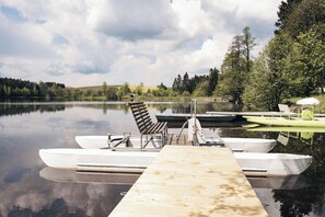 A calm lake with a dock, a bench, and several boats. - Hotel Medlov (Frysava pod Zakovou horou)