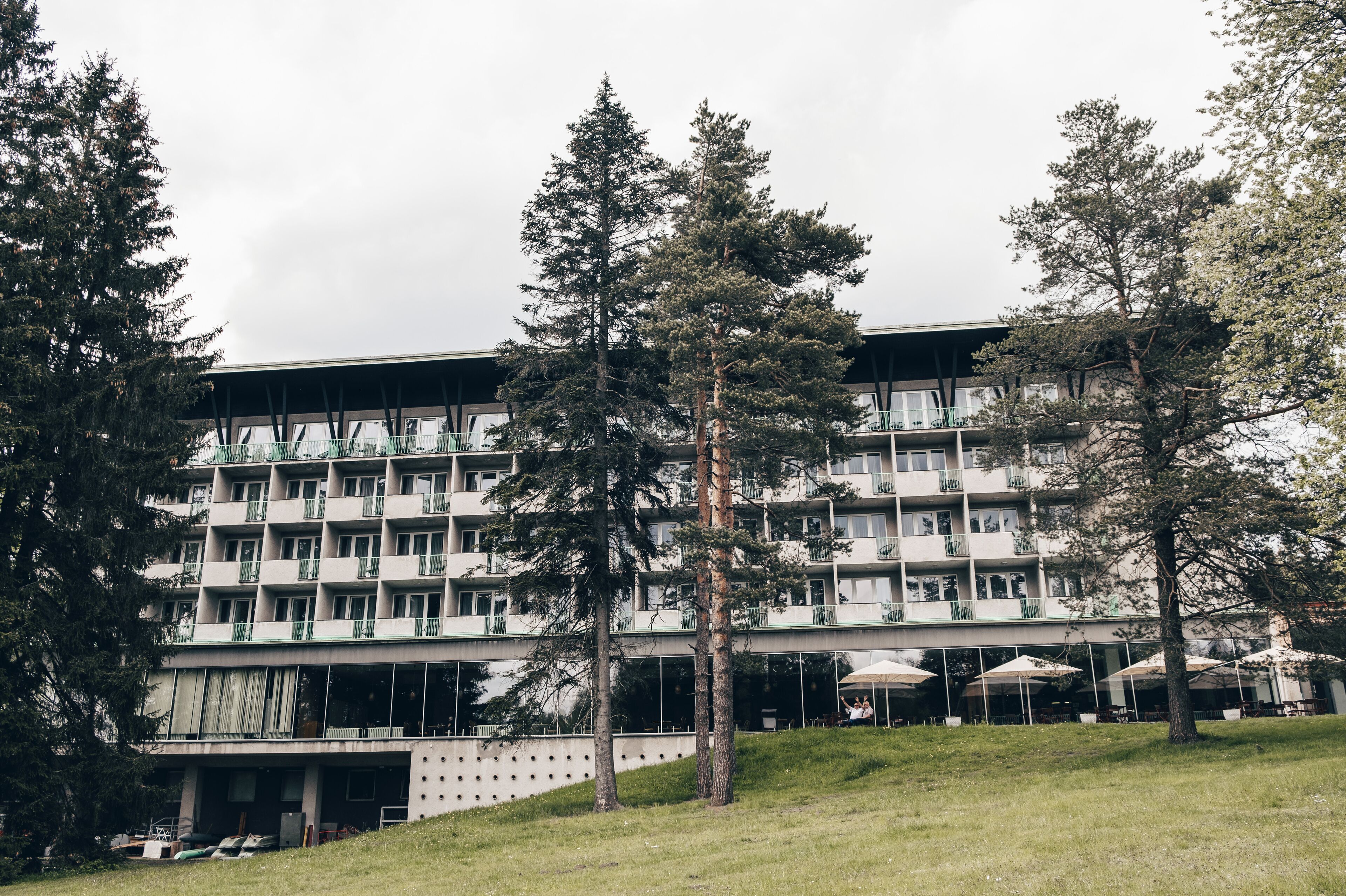 A multi-story hotel with a flat roof, balconies, and outdoor seating areas.