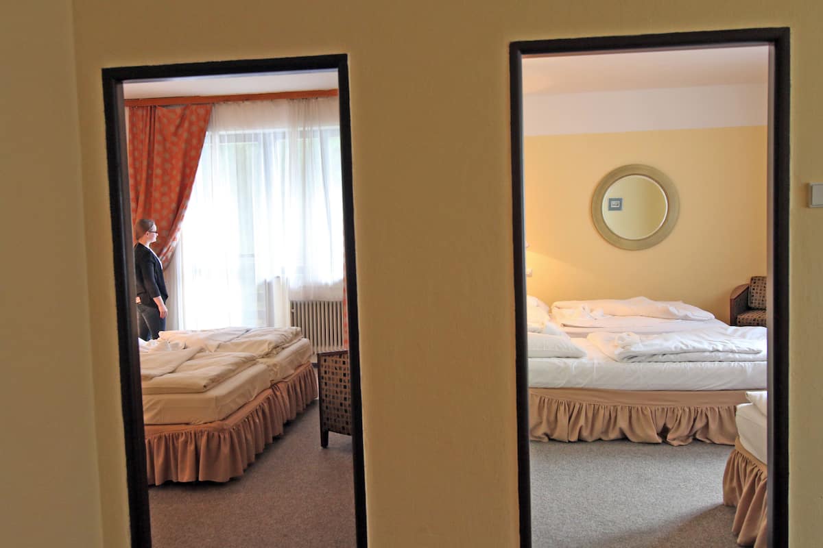 A hotel room with two beds, a mirror, and a window with curtains.