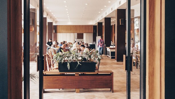 A hotel lobby with a wooden floor, a clock on the wall, and a seating area with plants. - Hotel Medlov (Frysava pod Zakovou horou)