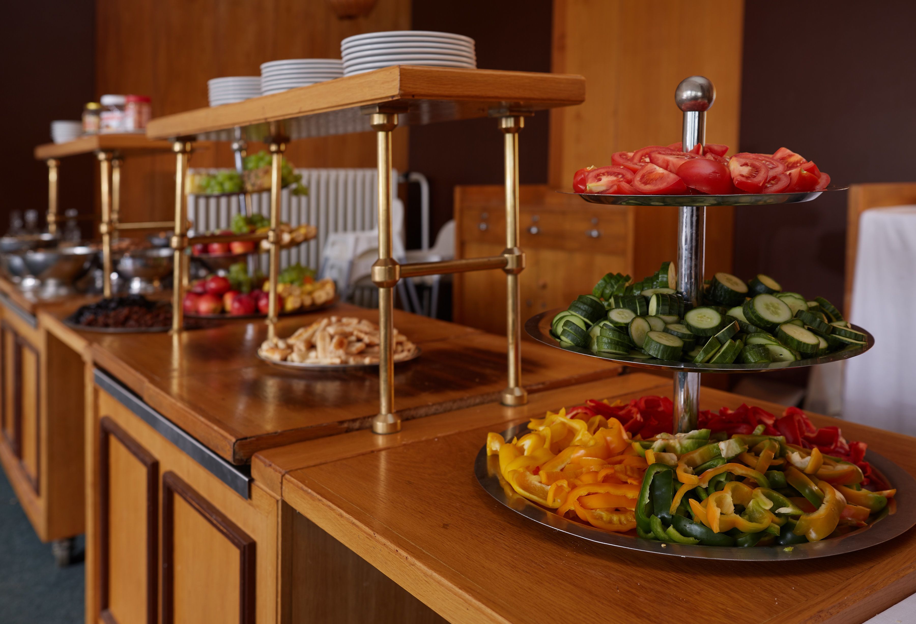 A buffet setup with multiple serving stations, including fruits, vegetables, and sliced meats.