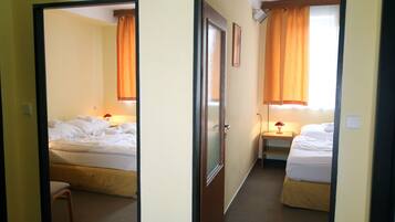 A hotel room with two beds, a chair, and a nightstand with a lamp.