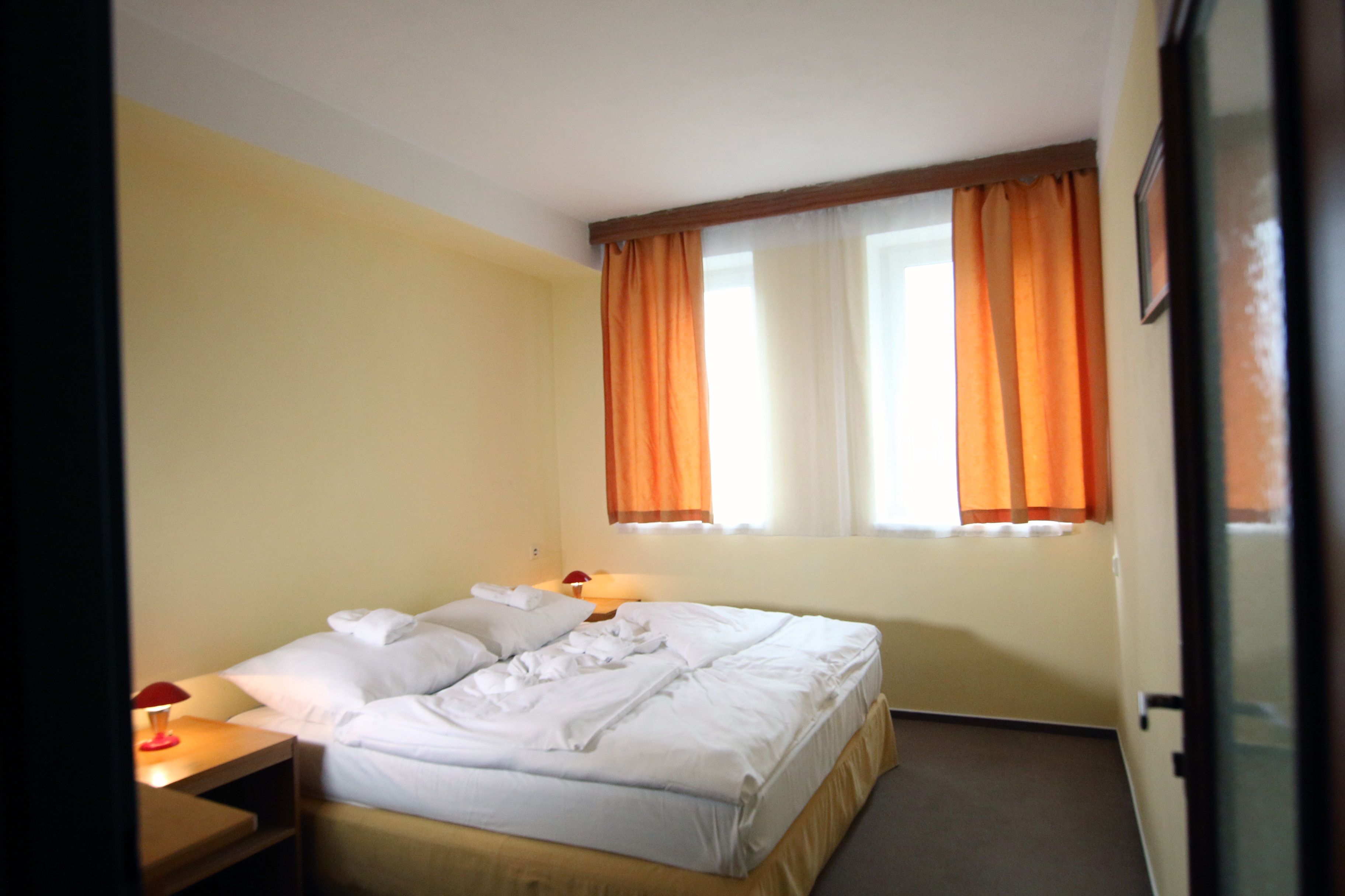 A hotel room with a bed, a nightstand, and a window with curtains.
