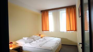 A hotel room with a bed, a nightstand, and a window with curtains.