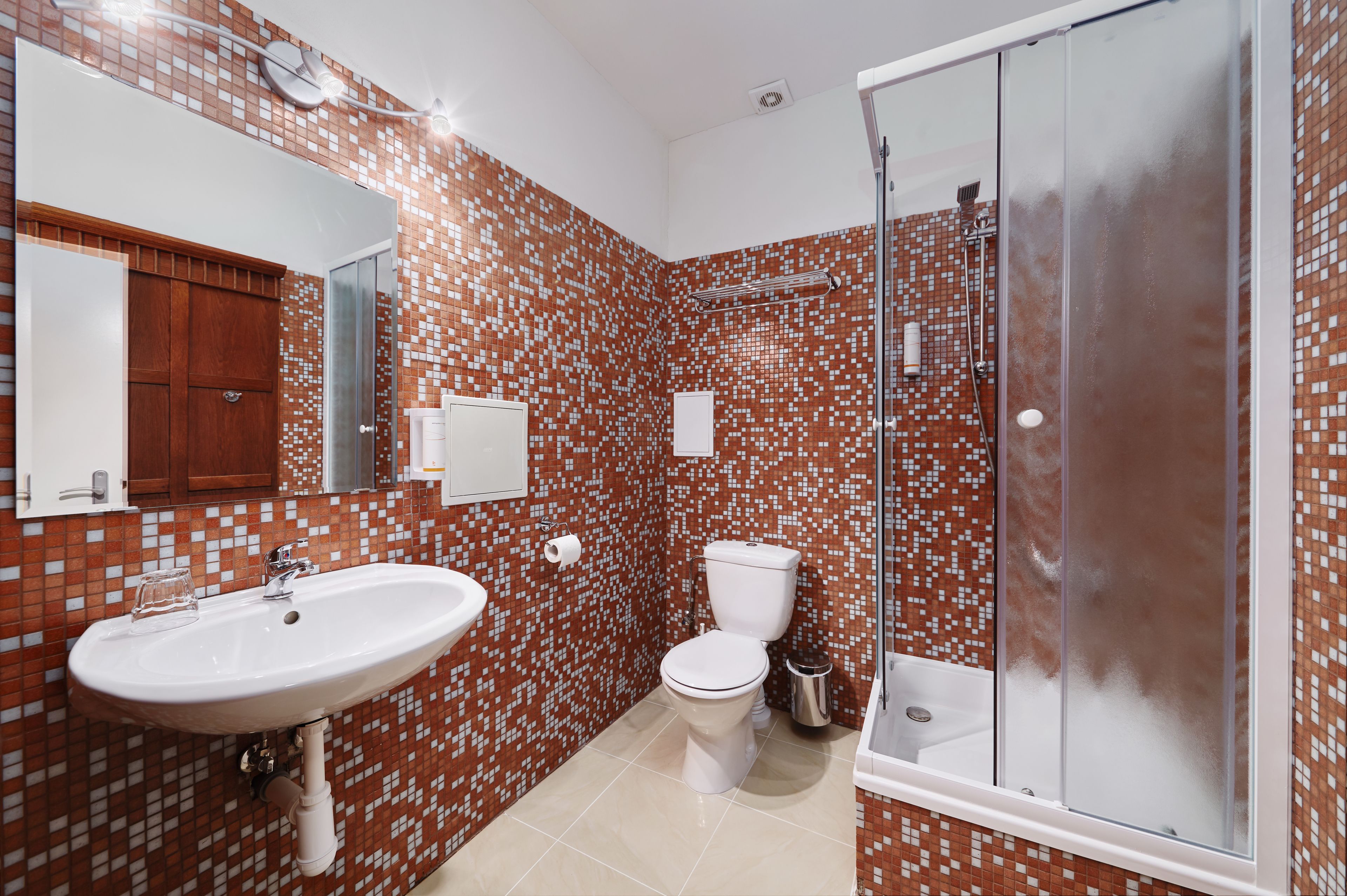 Un baño con salpicadero de azulejos, un lavabo, un inodoro y una ducha con mampara de cristal.