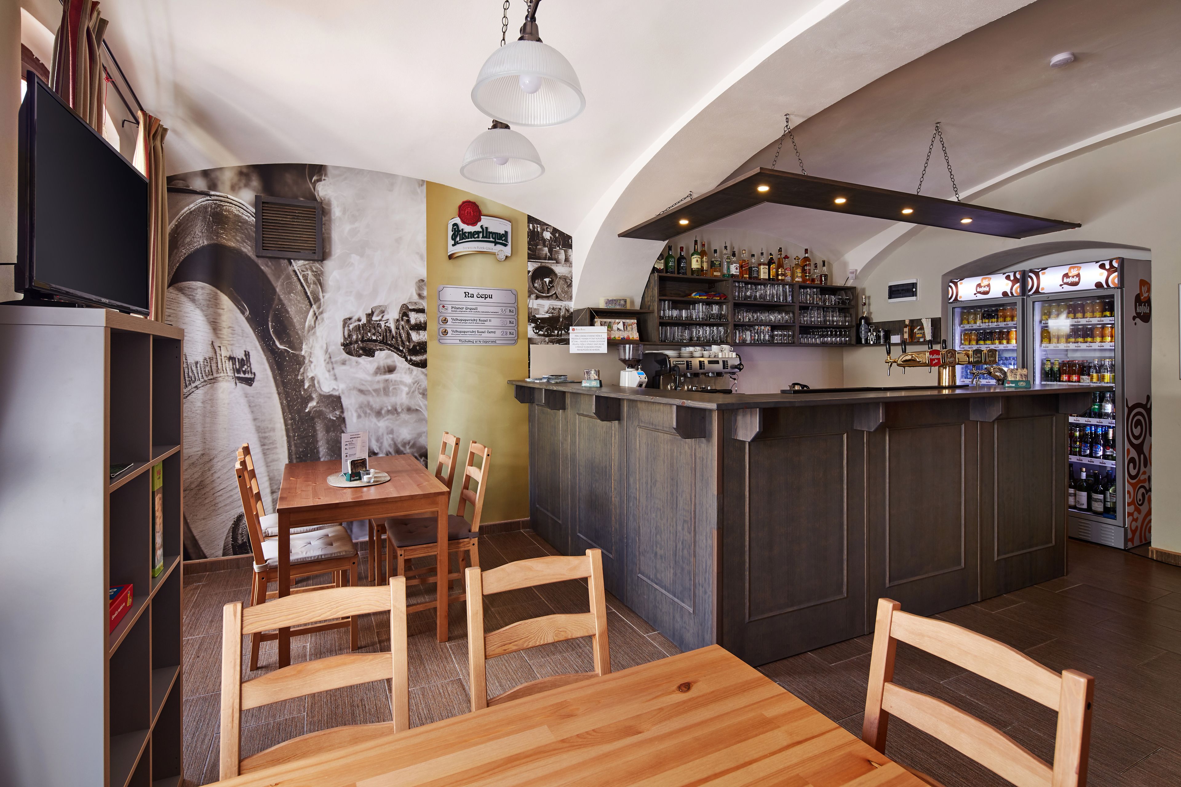 A restaurant with a bar area, wooden chairs, a counter, and a menu board.