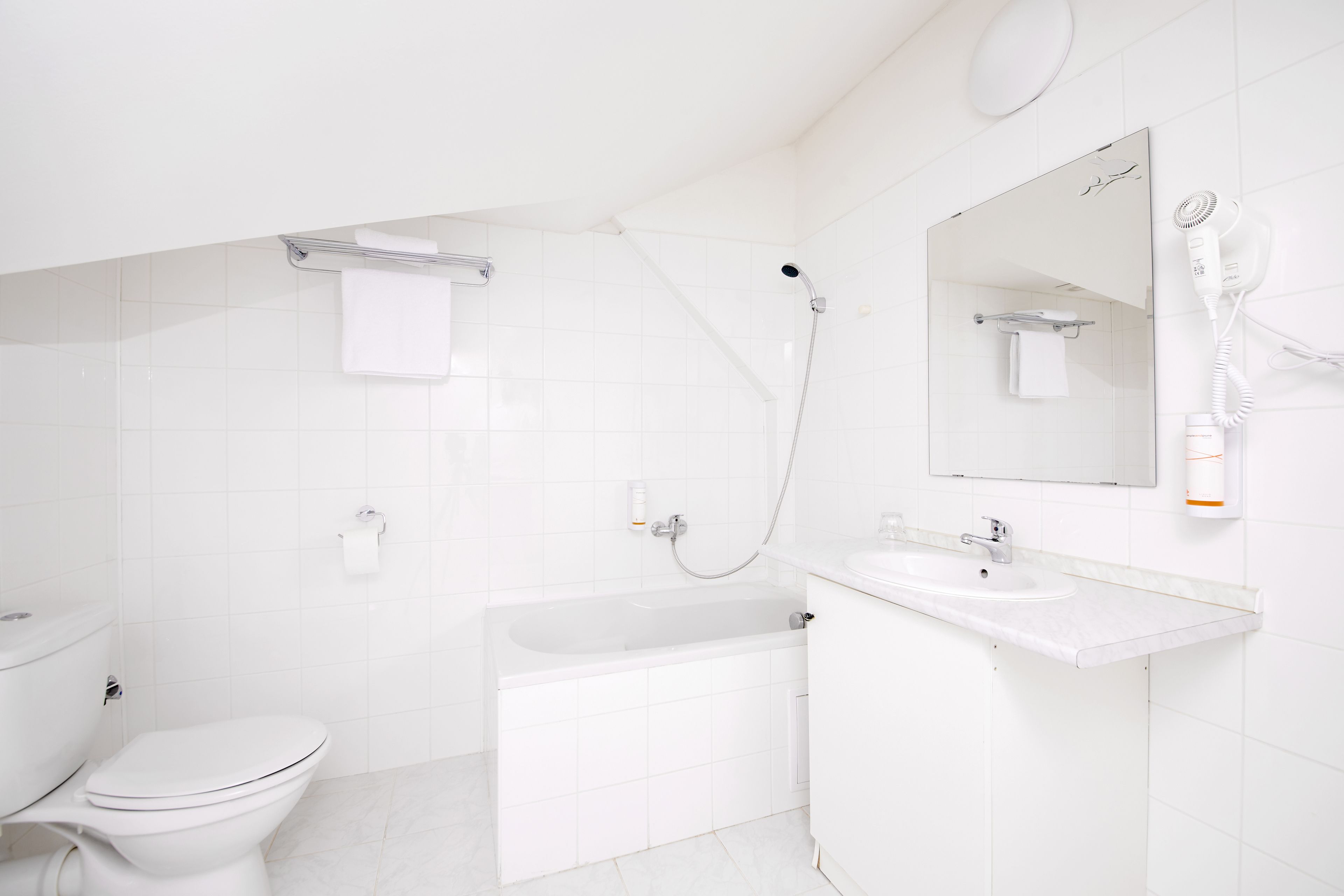 A modern bathroom with a toilet, bathtub, and a sink with a mirror.