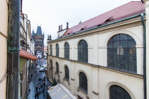 A narrow street with historic buildings, including a building with large arched windows and a red-tiled roof.