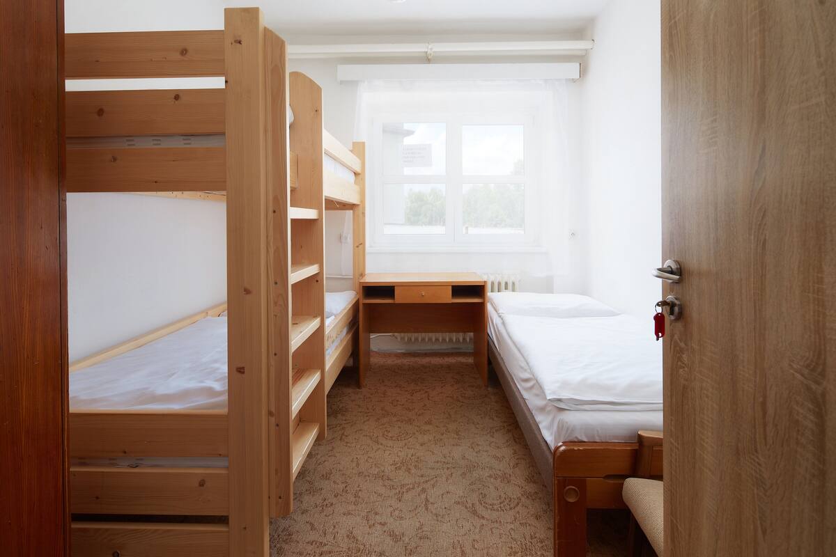 A room with bunk beds, a desk, and a window.