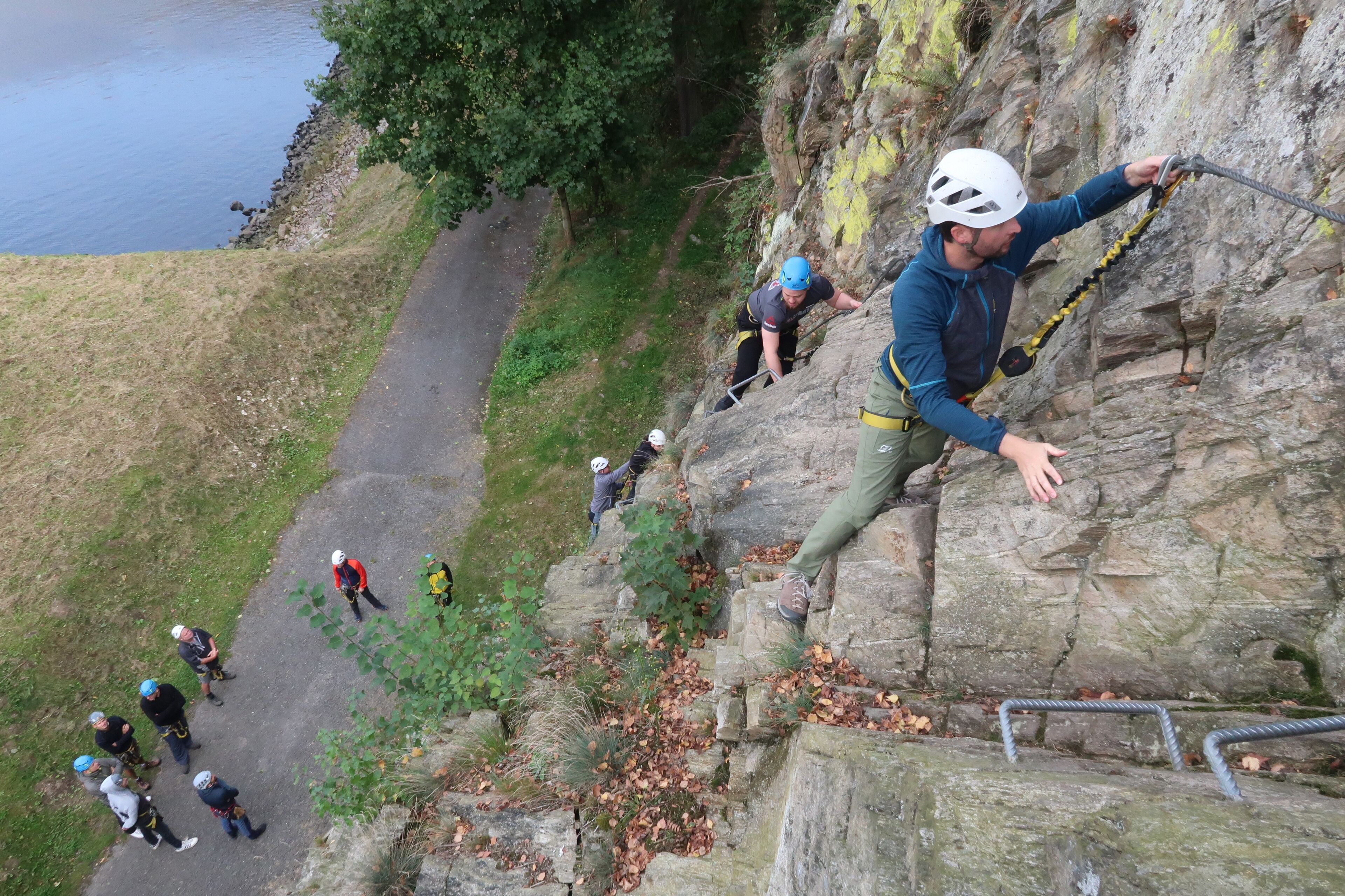A group of people climbing a rocky cliff with a path beside them.