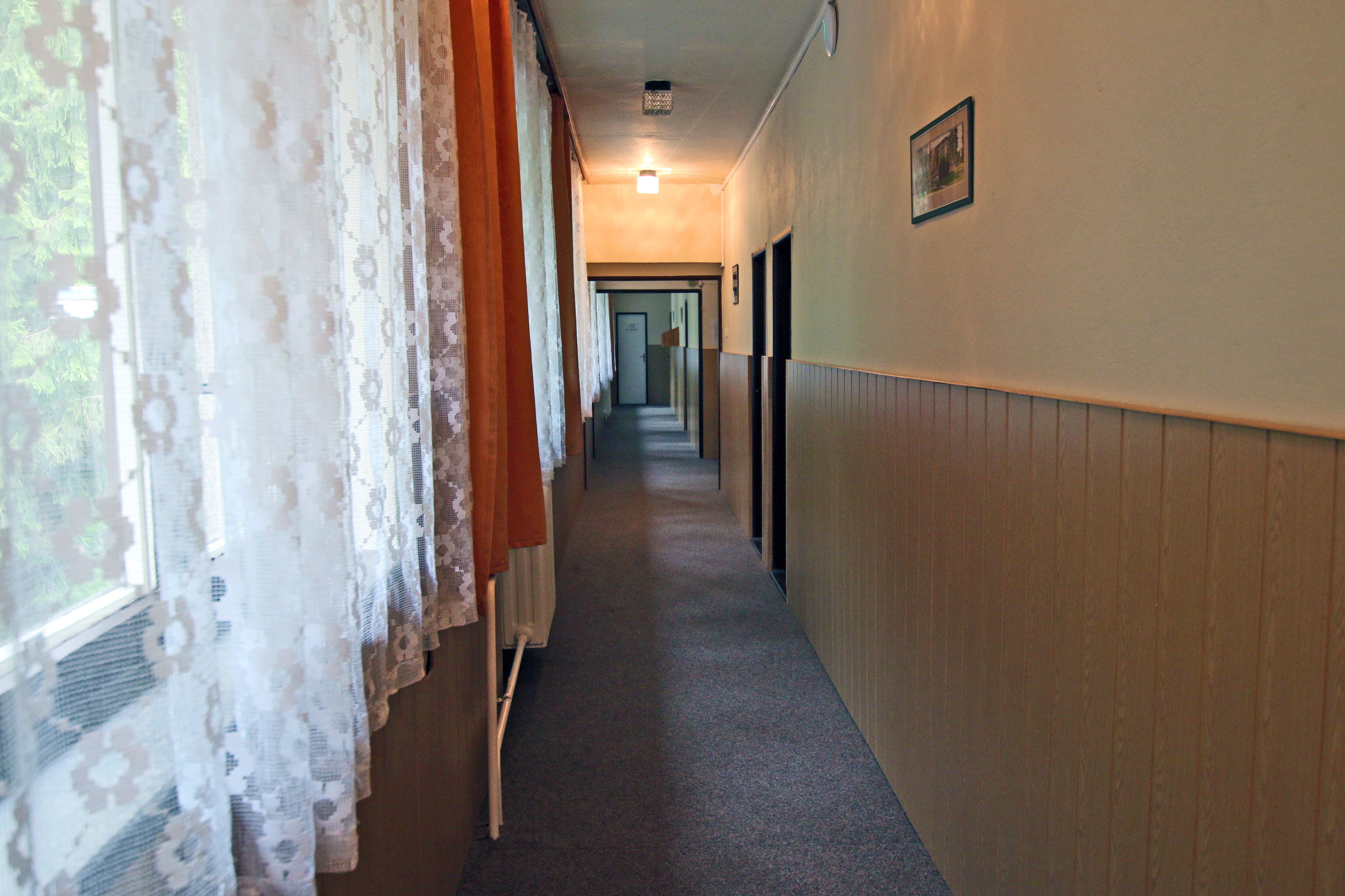A narrow hallway with patterned curtains on one side and a wooden panel wall on the other.
