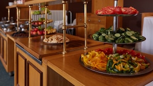 Un buffet avec plusieurs présentoirs où sont disposés différents plats, notamment des fruits, des légumes et des viandes en tranches.
