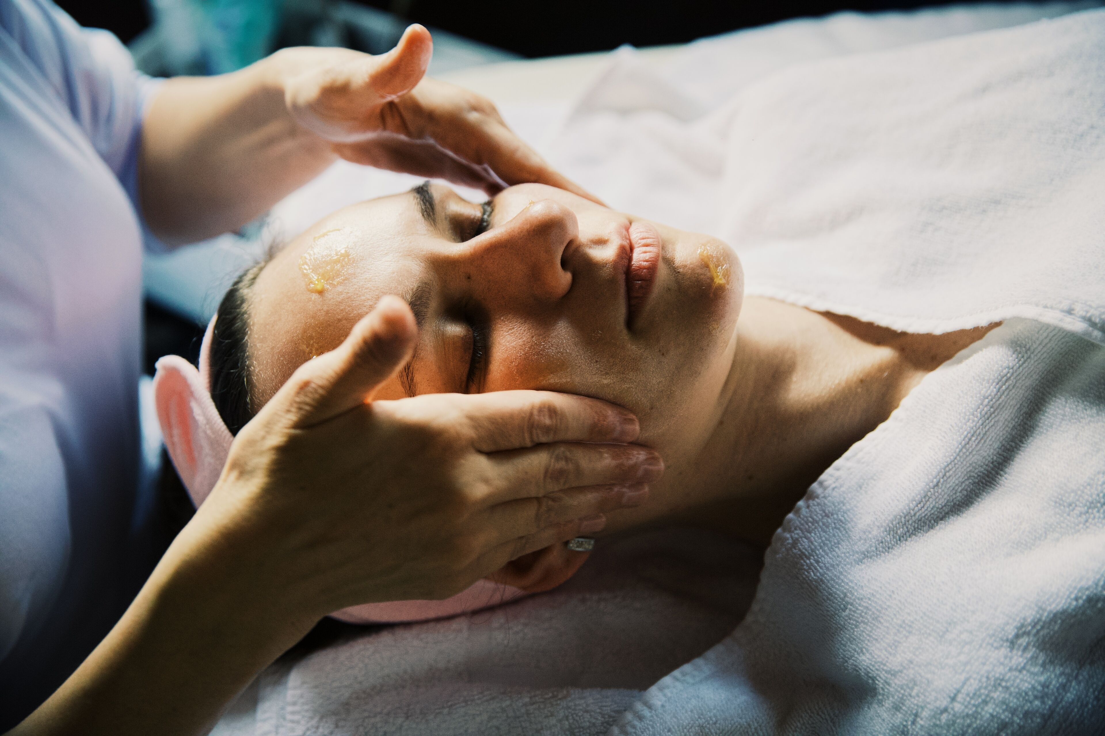 A person lying down with hands on their head, possibly receiving a massage.