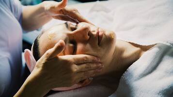 A person lying down with hands on their head, possibly receiving a massage.