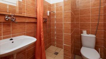 Un baño con lavabo, inodoro, ducha y cortina de ducha naranja.