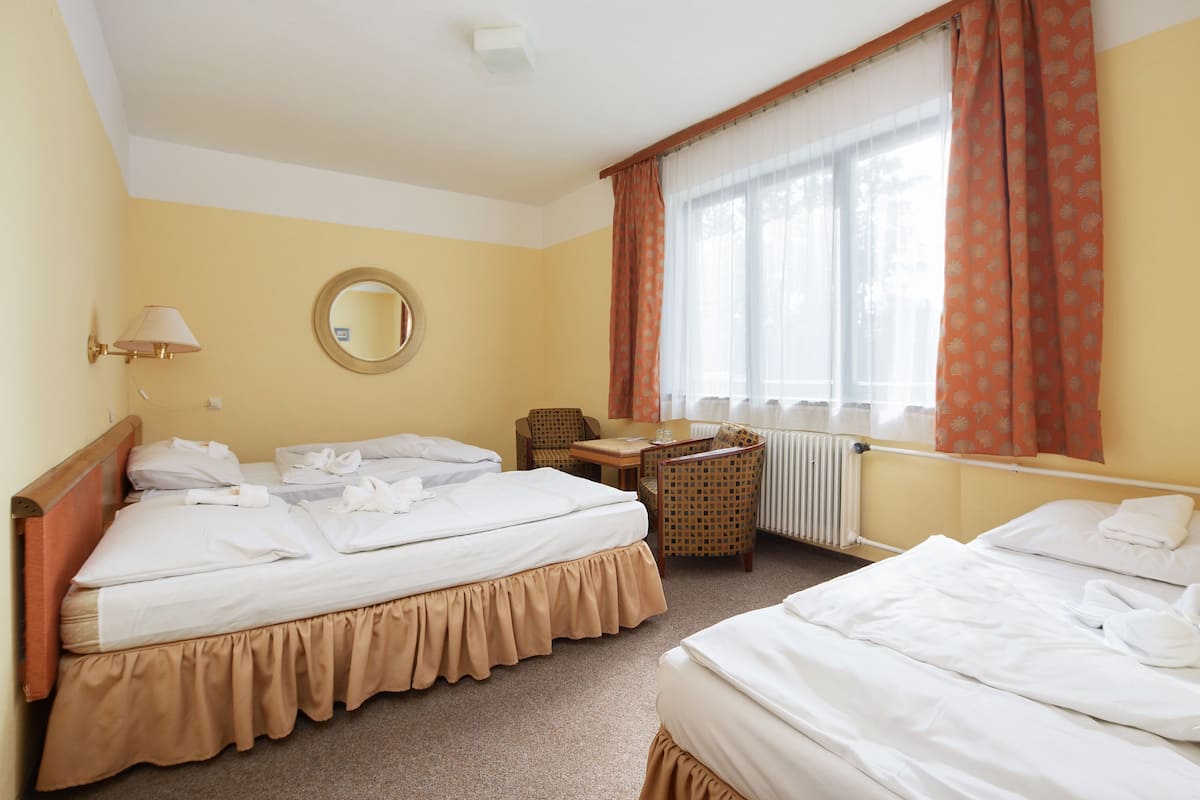 A hotel room with two beds, a round mirror, a desk, and a chair.