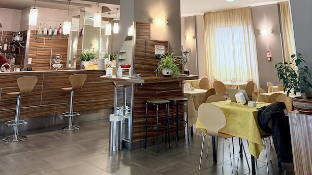A modern restaurant with a bar area, high chairs, and tables.