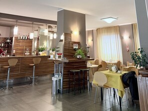 Un restaurant moderne doté d’un bar, de chaises hautes et de tables.