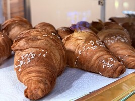 Esposizione di croissant con codette bianche, disposti su una superficie rivestita di carta.