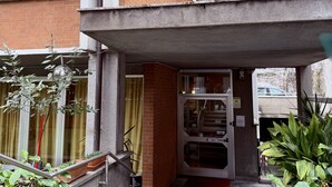 A building entrance with a concrete overhang, a glass door, and a metal staircase leading up.