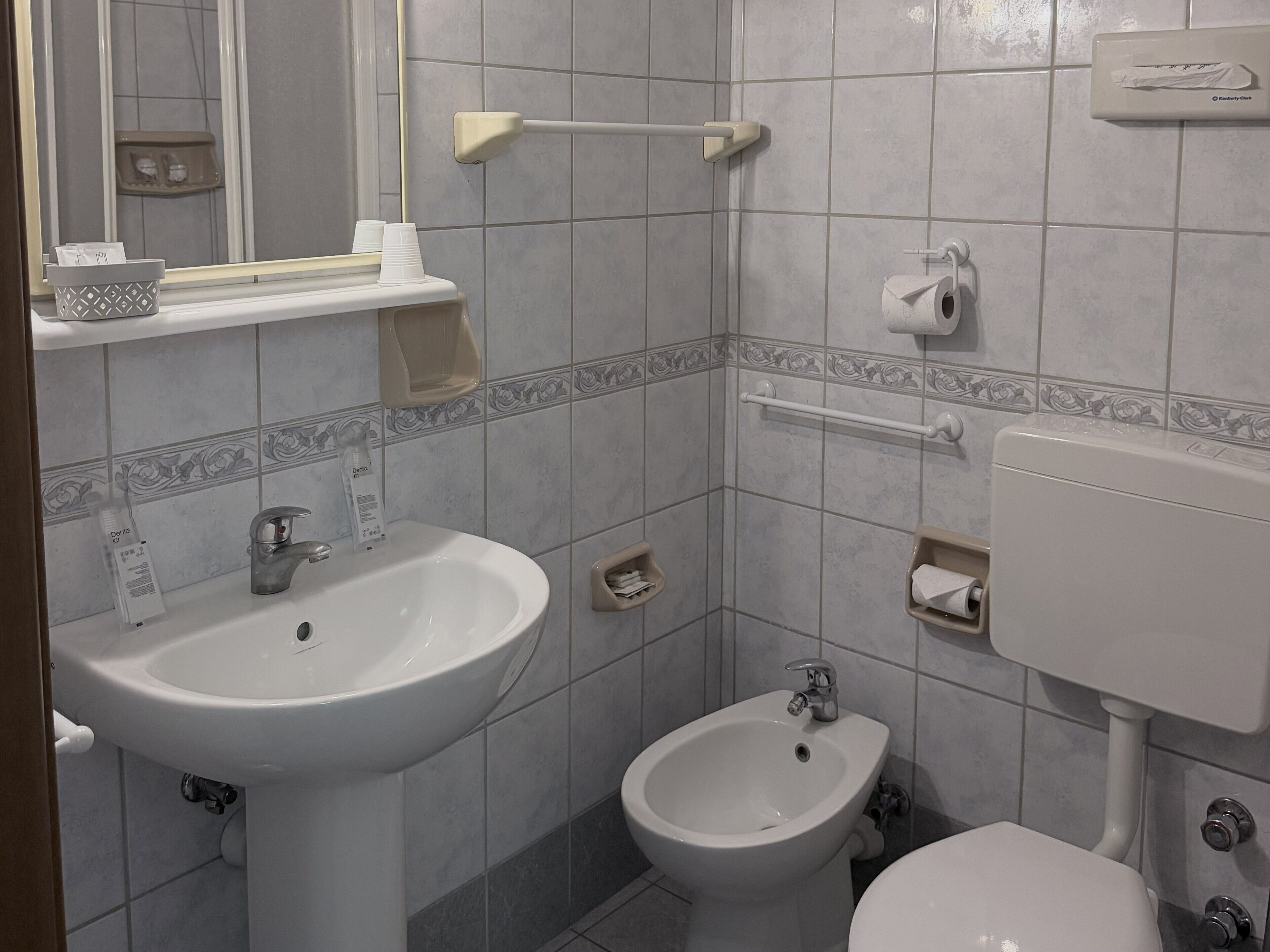 A bathroom with a sink, bidet, toilet, and a mirror.
