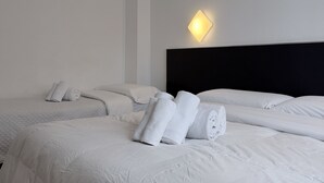 A hotel room with two beds, white linens, and a wall-mounted light fixture.
