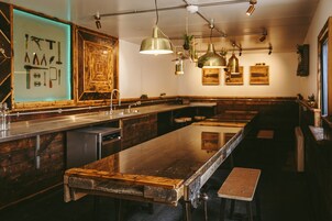 Um balcão comprido com banquetas, iluminação pendente e um armário de madeira com vitrine.