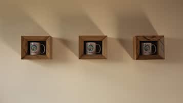 Tres vitrinas de madera con tazas sobre una pared lisa.