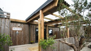 Un bâtiment en bois sur lequel est apposée une enseigne indiquant : « Le café-restaurant The Toolshed. »