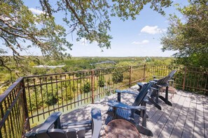 A deck with outdoor seating, overlooking a river and greenery.
