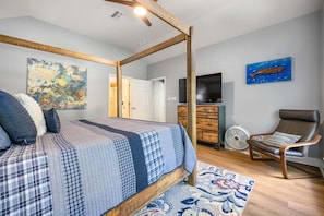 A bedroom with a four-poster bed, a dresser, a chair, and a television.