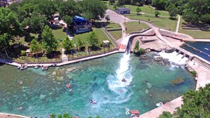 A water park with a waterfall, clear water, and people on rafts. - Gruene Vista on the Guadalupe - 1 mi to Gruene, 3 mi to Downtown NBTX, Panoramic Hill Country Views (New Braunfels)