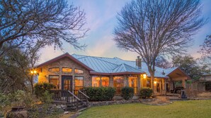 A two-story house with a metal roof, brick exterior, and a covered porch. - Gruene Vista on the Guadalupe - 1 mi to Gruene, 3 mi to Downtown NBTX, Panoramic Hill Country Views (New Braunfels)
