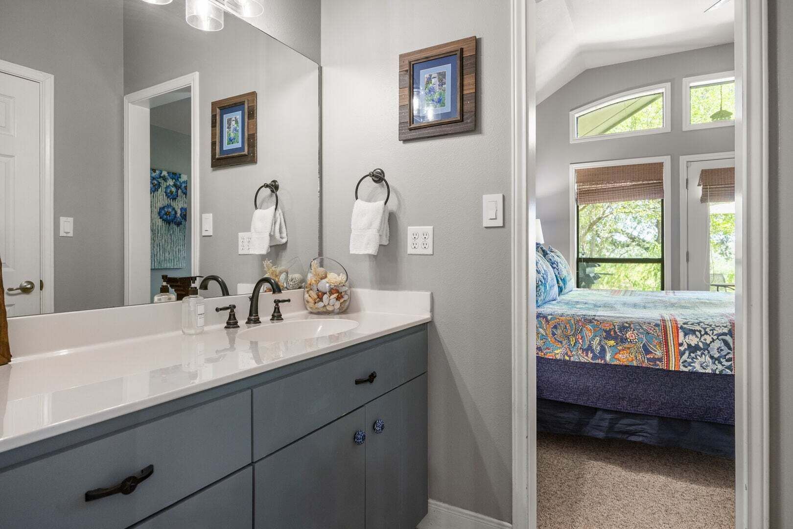 A bathroom with a large mirror, a sink, and a window.