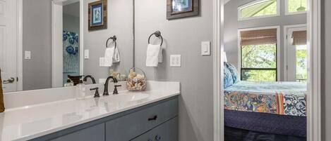A bathroom with a large mirror, a sink, and a window.