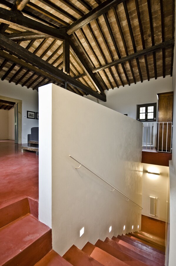 A staircase with a wooden handrail, a white wall, and a red floor. - Relais Villa Ambrosetti (Verona)