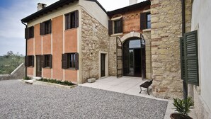 A two-story stone building with a stone facade, a balcony, and a gravel driveway. - Relais Villa Ambrosetti (Verona)