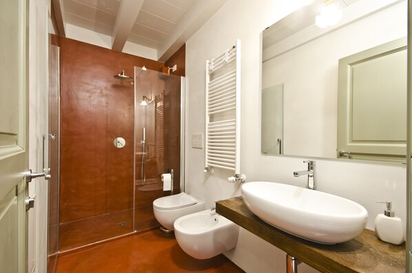 A modern bathroom with a wooden shower enclosure, a white toilet, a bidet, and a large oval sink with a wooden countertop. - Relais Villa Ambrosetti (Verona)