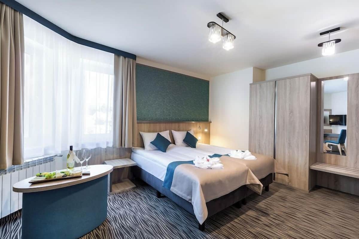 A hotel room with a bed, bedside table, and a mirror.