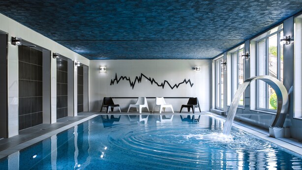 An indoor swimming pool with clear water, a wave machine, and seating areas. - Krasicki Hotel Resort & SPA (Swieradow-Zdroj)