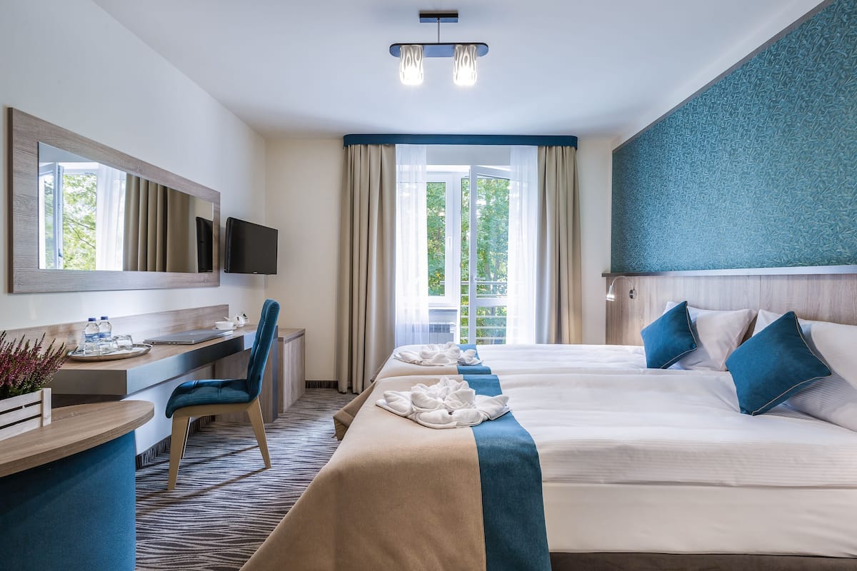 A hotel room with a bed, desk, chair, and a television.