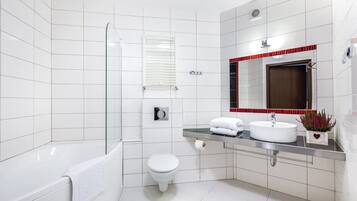 Un baño moderno con bañera, inodoro y tocador con espejo y lavabo.