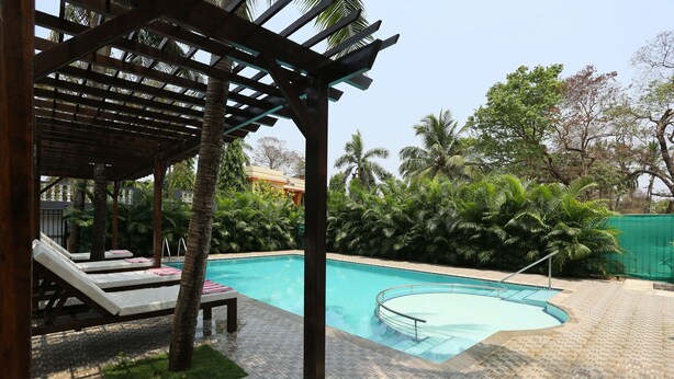 Zona de piscina con sillones de descanso y una pérgola.