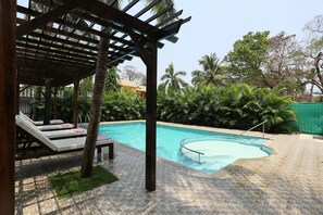 Zona de piscina con sillones de descanso y una pérgola.