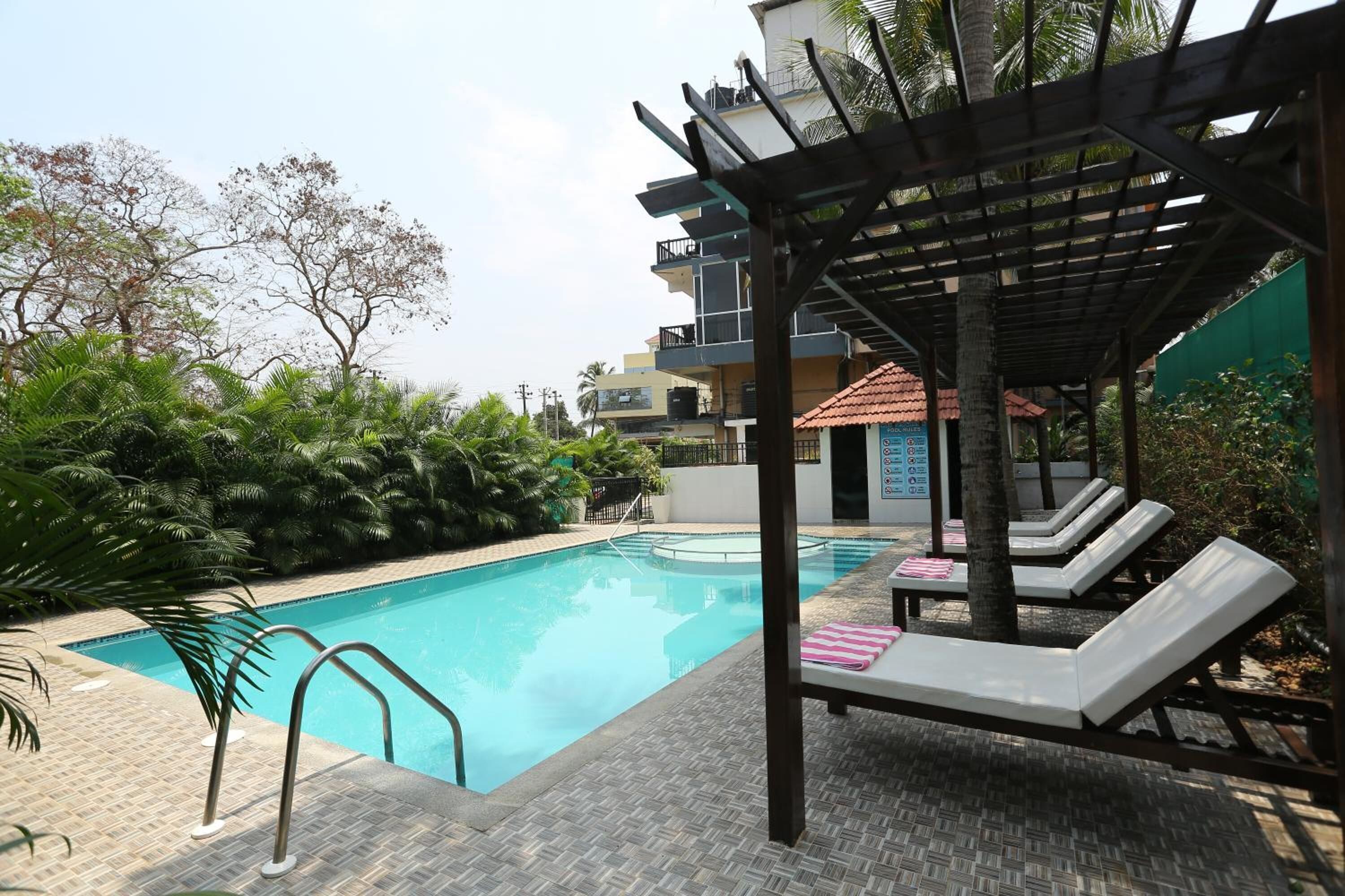 A swimming pool with lounge chairs and a pergola.