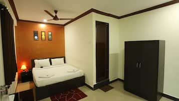 Una habitación de hotel con cama, armario, mesita de noche, lámpara y ventilador de techo.