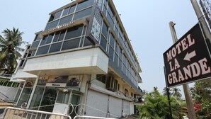 Un edificio de varios pisos con un cartel que indica 'Motel La Grande' y un letrero de 'Bienvenido' en la entrada.