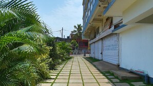 Un sendero estrecho bordeado de palmeras y un edificio con una antena parabólica.