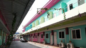 A row of colorful buildings with balconies, air conditioning units, and potted plants. - White Square Rayong (Rayong)