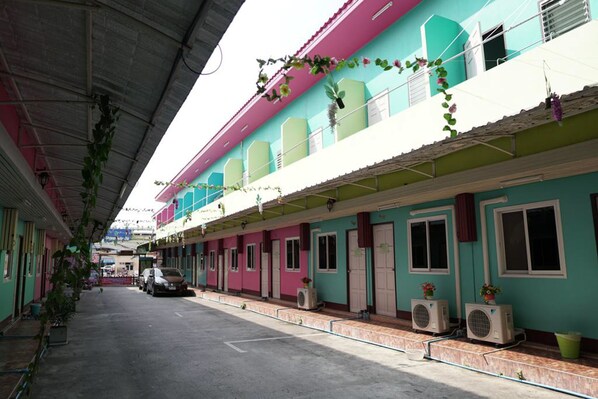 A row of colorful buildings with balconies, air conditioning units, and potted plants. - White Square Rayong (Rayong)
